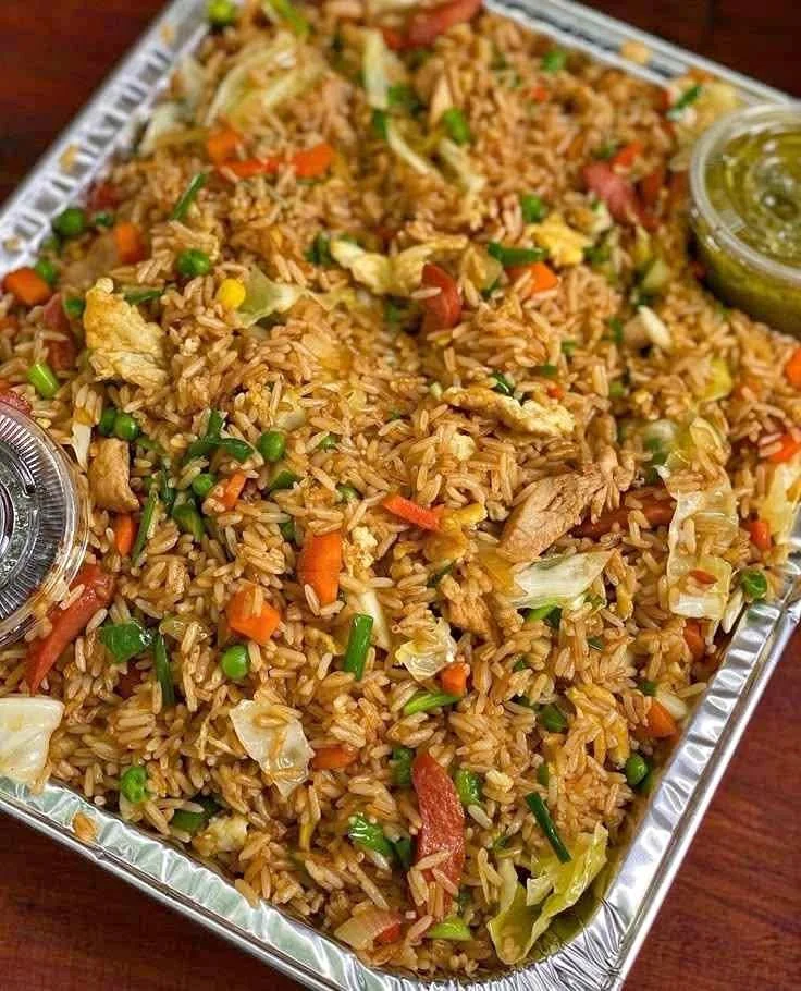 Delicious Fried Rice with Mixed Vegetables, Chicken, and Condiments in Aluminum Tray